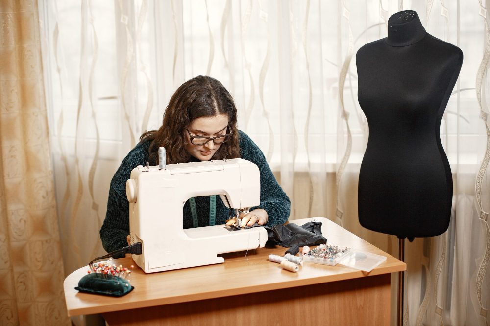 Fabric in a typewriter. Woman deftly works with a sewing machine. Woman with glasses.<br />
